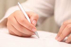 Businesswoman viewing the contract before signing. Close-up. Focus on pen. Shallow depth of field. EOS 5D